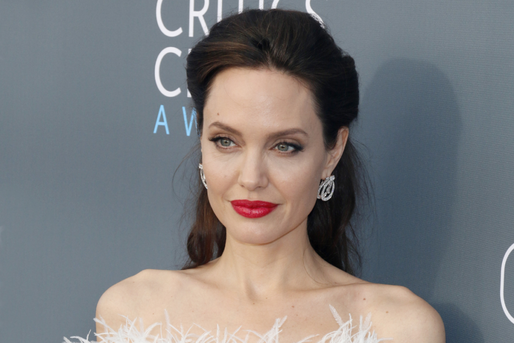 9 famosos do signo de Gêmeos 32 Angelina Jolie com cabelo preto e batom vermelho posando para foto
