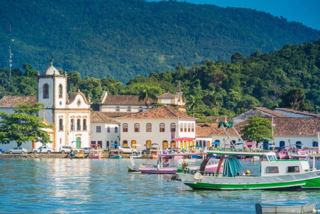 5 destinos românticos para visitar no Dia dos Namorados 21 Vista de Paraty, RJ, com barcos no mar, igrejas históricas e montanhas ao fundo