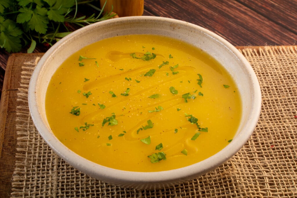 8 sopas e cremes detox para a segunda-feira 6 Recipiente branco com sopa amarela polvilhada com coentro