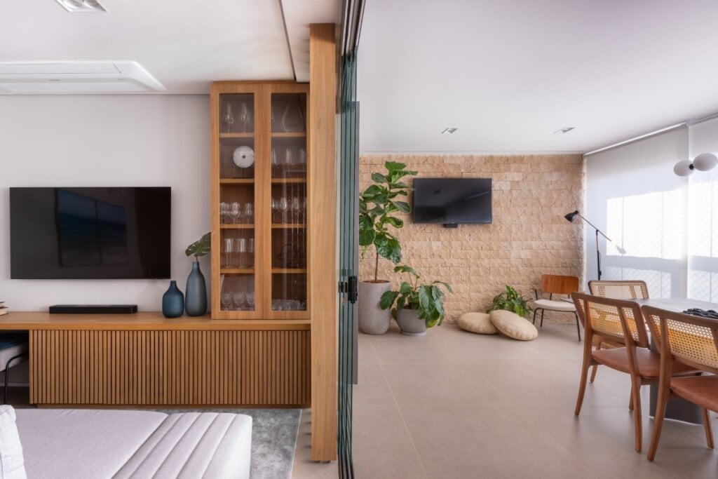 4 dicas práticas para aquecer a casa no inverno 17 Ambiente com porta de vidro separando dois espaços integrados, com móveis em madeira clara e plantas
