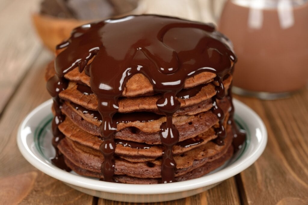 7 receitas ricas em proteínas para o lanche da tarde 6 panquecas de chocolate com calda de chocolate empilhadas