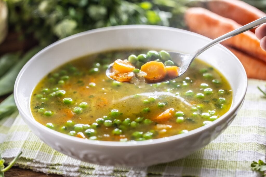 9 receitas de sopas e caldos para o jantar 6 Recipiente branco com sopa de ervilha com cenoura