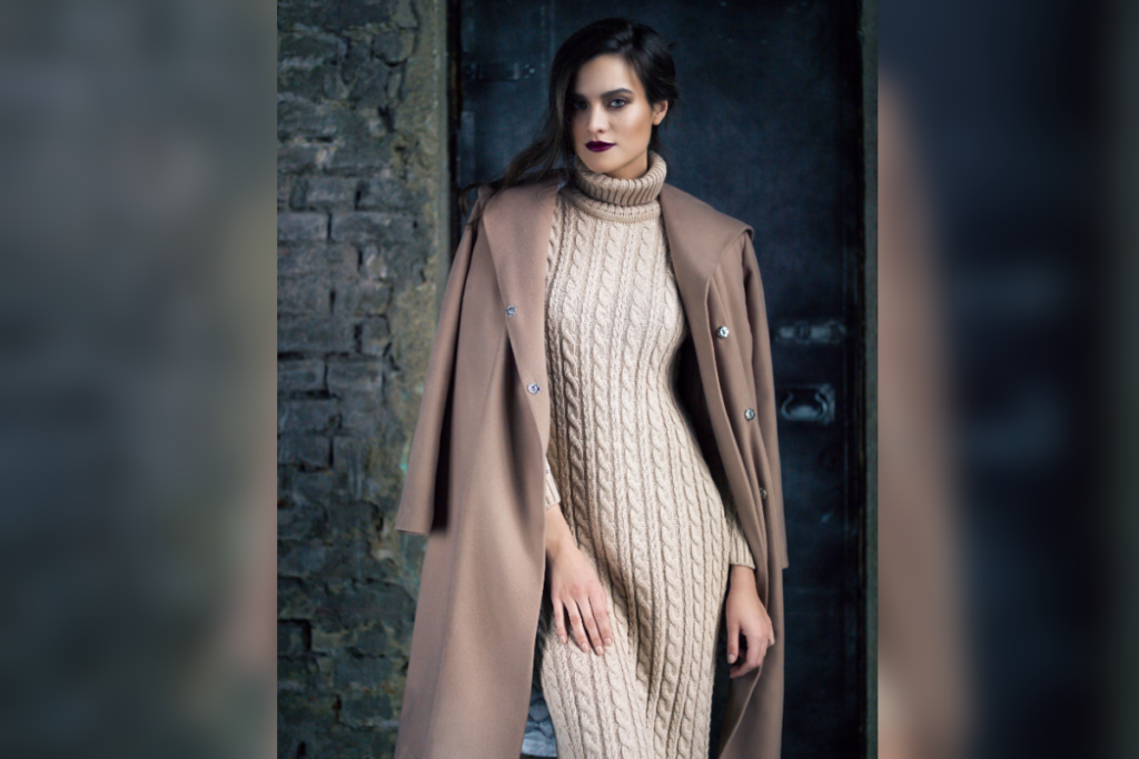5 tendências de moda casual para o inverno 21 Mulher de vestido longo de tricô e casaco sobre os ombros em ambiente com tijolos